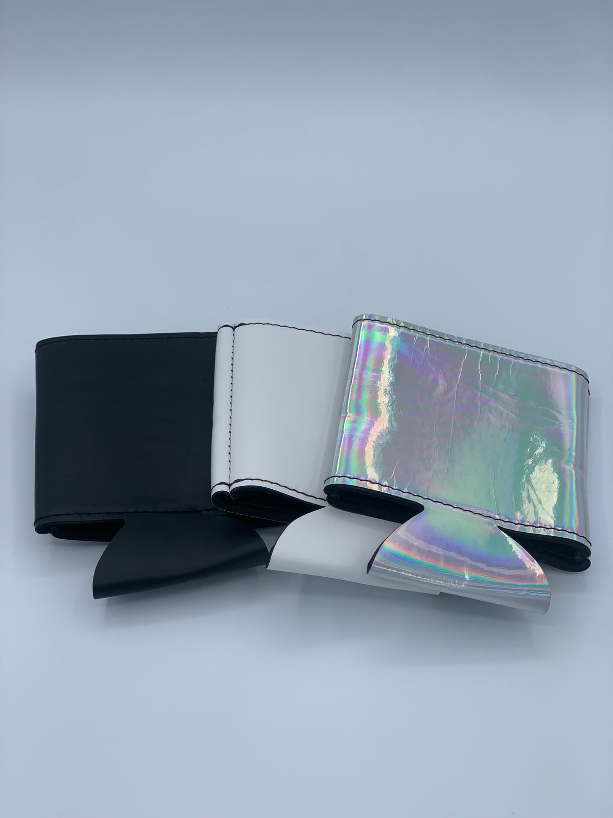 Black, White, and Holographic leatherette can coolers shown together to compare available finishes.