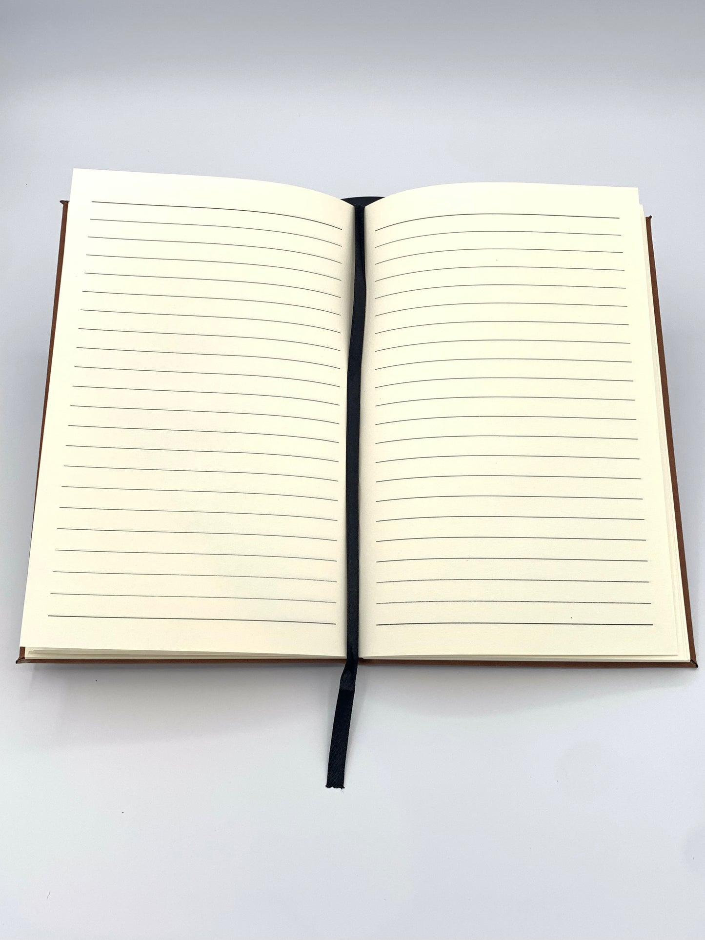 Open leatherette journal showing the lined 80 GSM interior pages and attached ribbon bookmark.