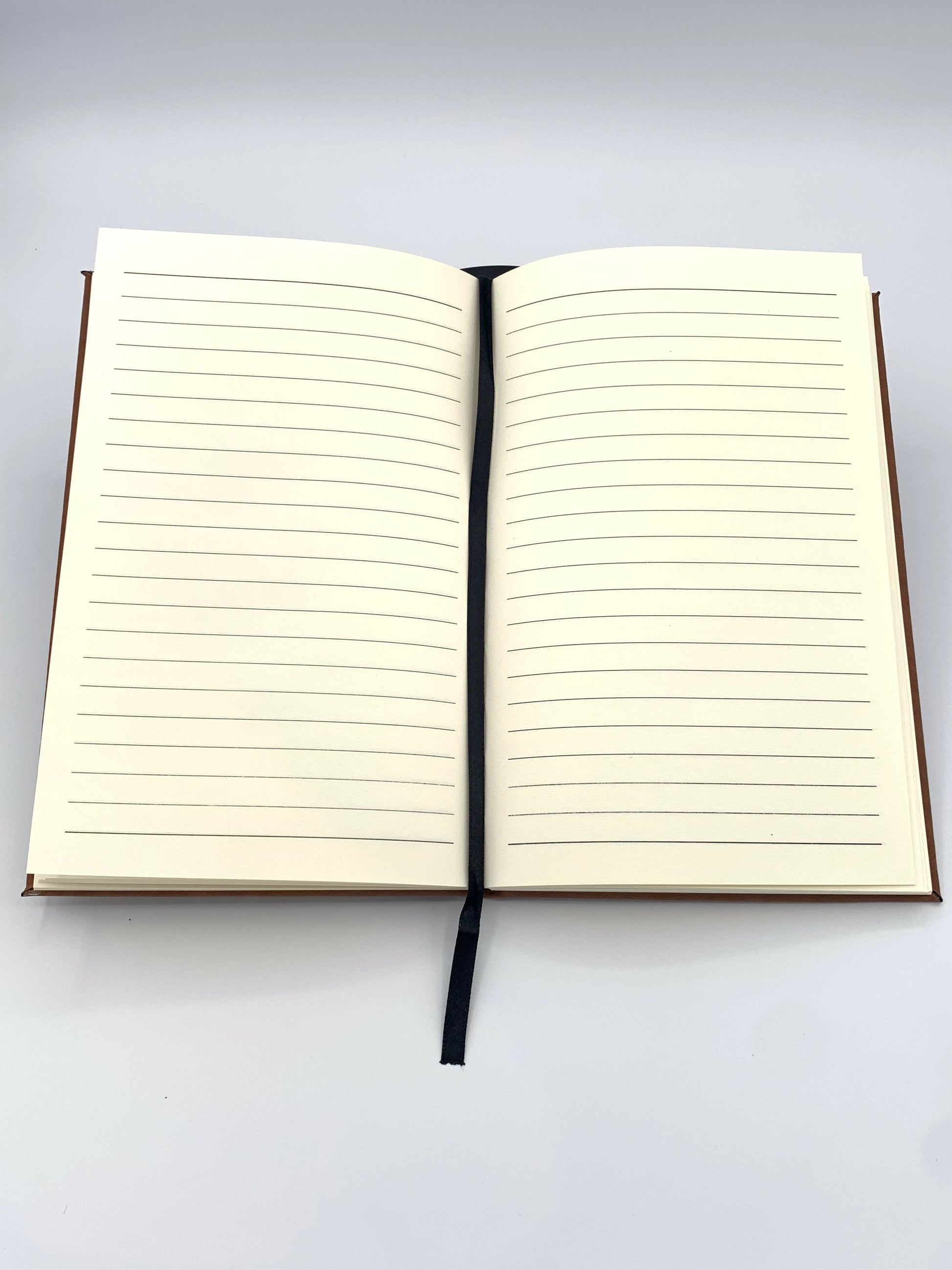 Open leatherette journal showing the lined 80 GSM interior pages and attached ribbon bookmark.