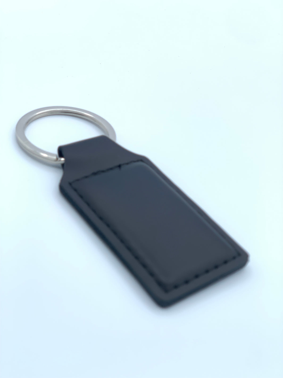 Black leatherette keychain shown with attached metal key ring and stitched personalization area.