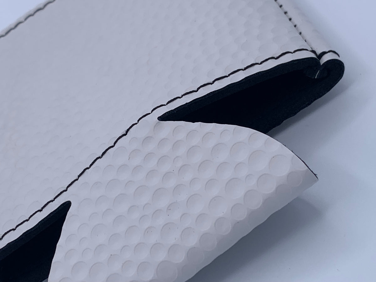 Close-up of the White Golf Ball Textured leatherette finish showing its raised golf-inspired surface texture and black interior.