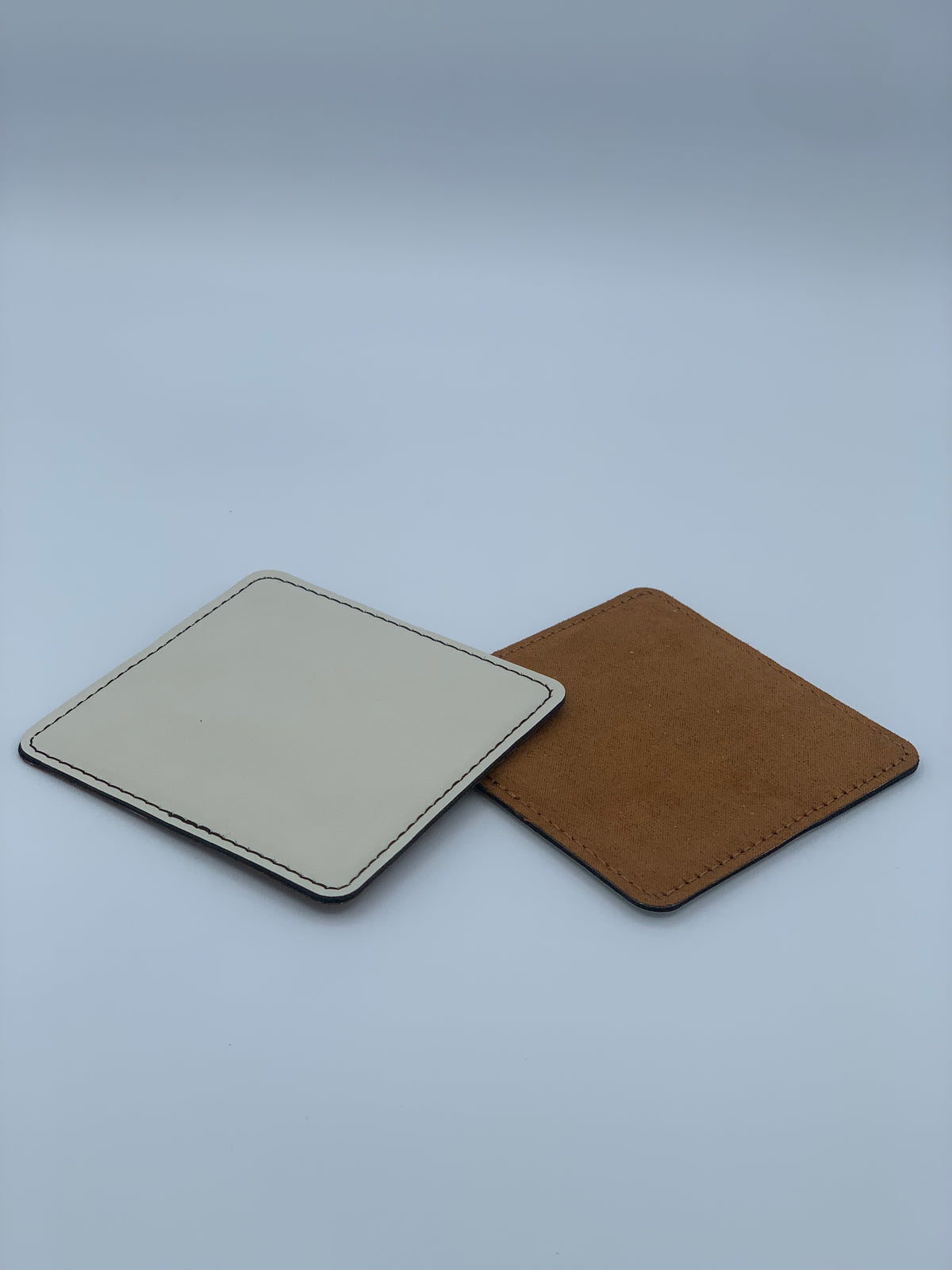 Square leatherette coasters shown in light and rawhide colored bottom
